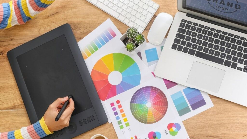 Graphic design workspace showing colour palette, tablet, and marketing charts